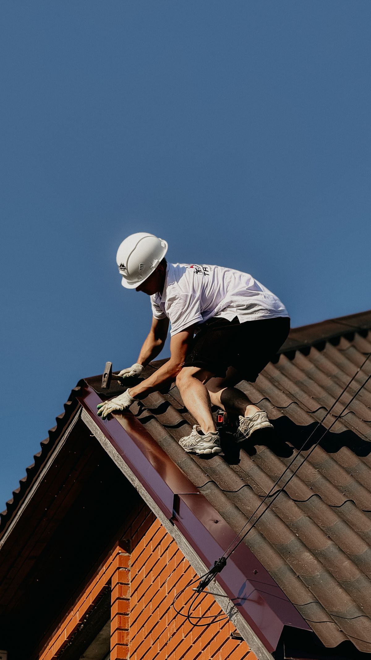 Dakspecialist met helm werkt veilig op een pannendak